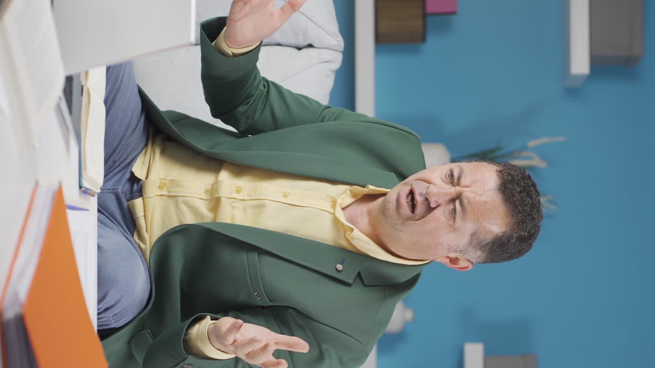 홈 오피스 직원의 수직 비디오  ⁇ 은이가 나쁜 소식을 읽고 좌절감을 느 ⁇ 니다.