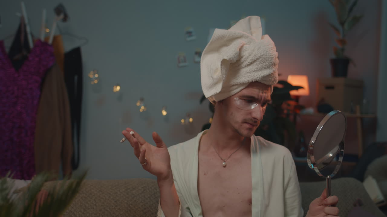 Man with towel on head smoking while holding a mirror