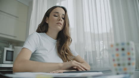 Stressed-woman-closing-laptop-and-drinking-cup-of-tea-at-home-workplace