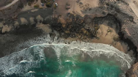 Costa-Rocosa-Oscura-Contrasta-Aguas-Turquesas-Con-Olas-Blancas-De-Espuma