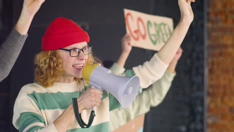 young environmental activist holding megaphone and protesting with her friends against climate change inaction