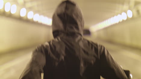 male in a hoodie running down a tunnel