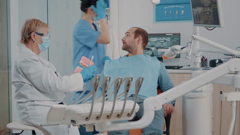 dentist showing correct way to clean denture with toothbrush