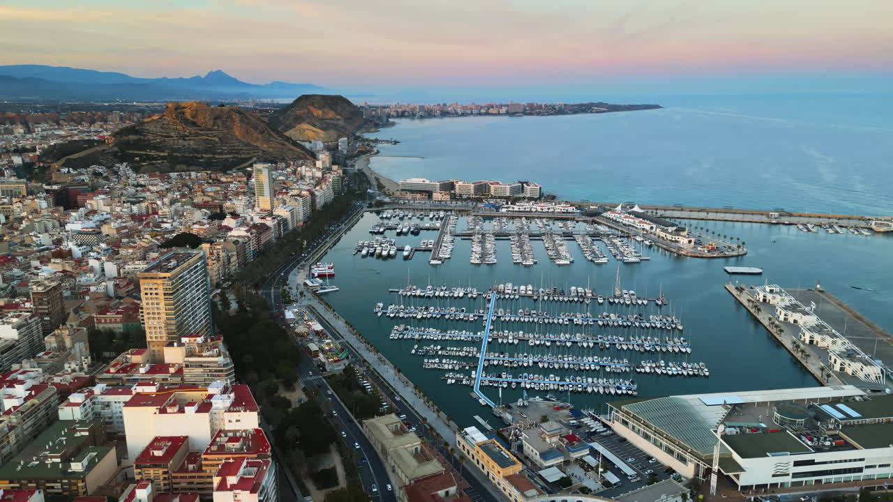 Aerial drone view of the Port of Alicante and the buildings in the city in the evening