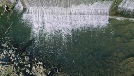 an aerial downward view of a man made waterfall for a mill, on a sunny day