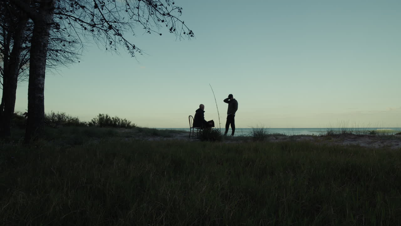 Silhouette Of Two Fishermen Waiting Patiently For The Fish To Bite At Dawn