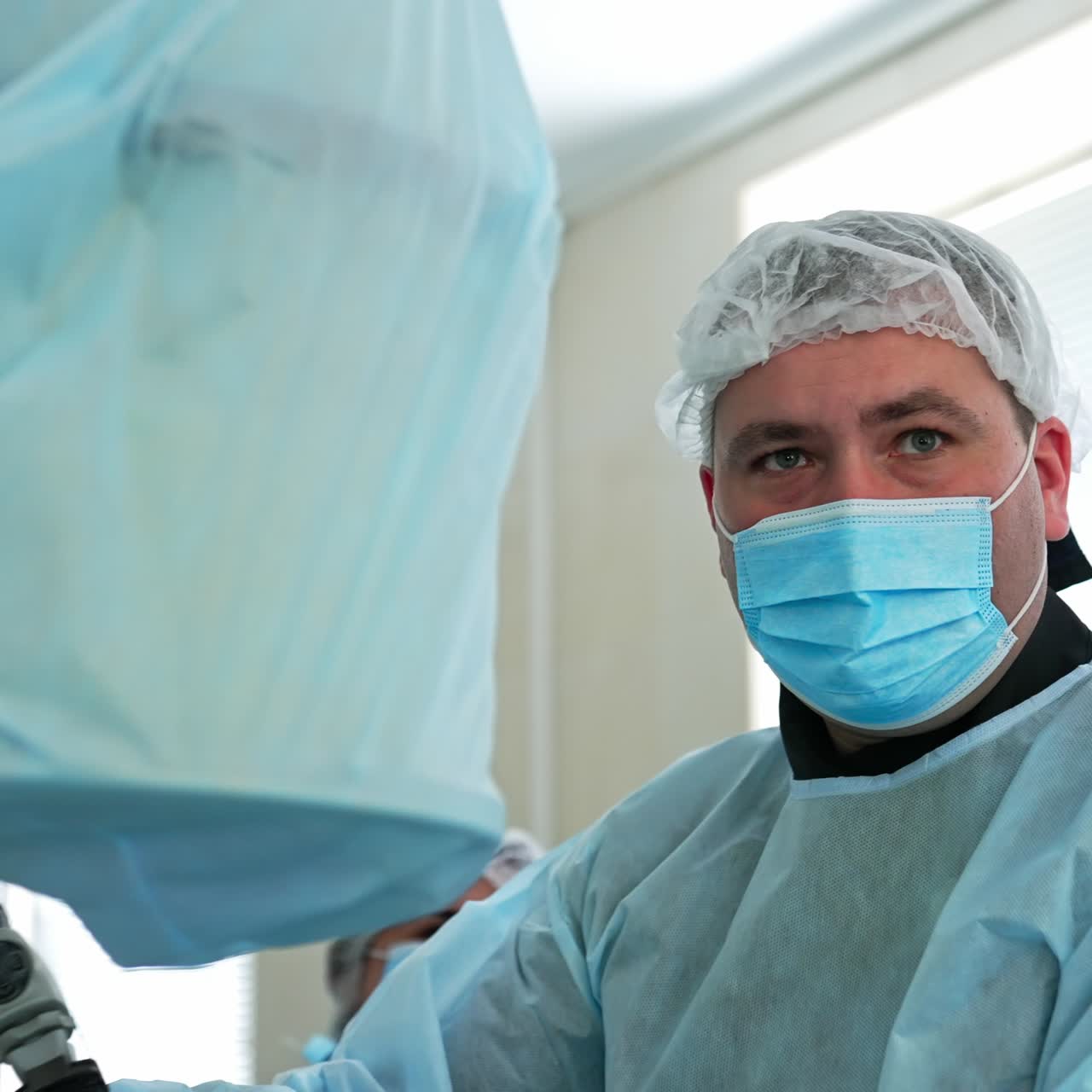 Intense look of a surgeon applying instrument to a patient at surgery. Portrait of a doctor totally focused at his work