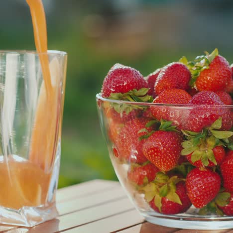 Pour-The-Juice-Into-A-Glass-Next-To-A-Plate-Of-Fresh-Strawberries