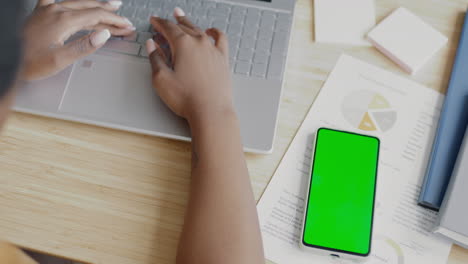 woman working on a laptop and smartphone with documents