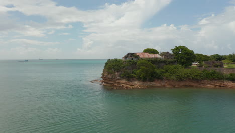 la toma aérea revela una vista de un edificio abandonado en la bahía costera rocosa de antigua y bermudas.
