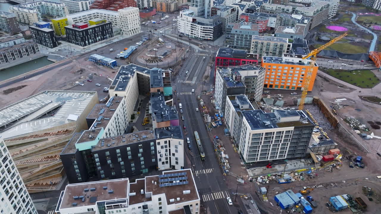 Aerial view following a tram driving past a construction site in cloudy Helsinki