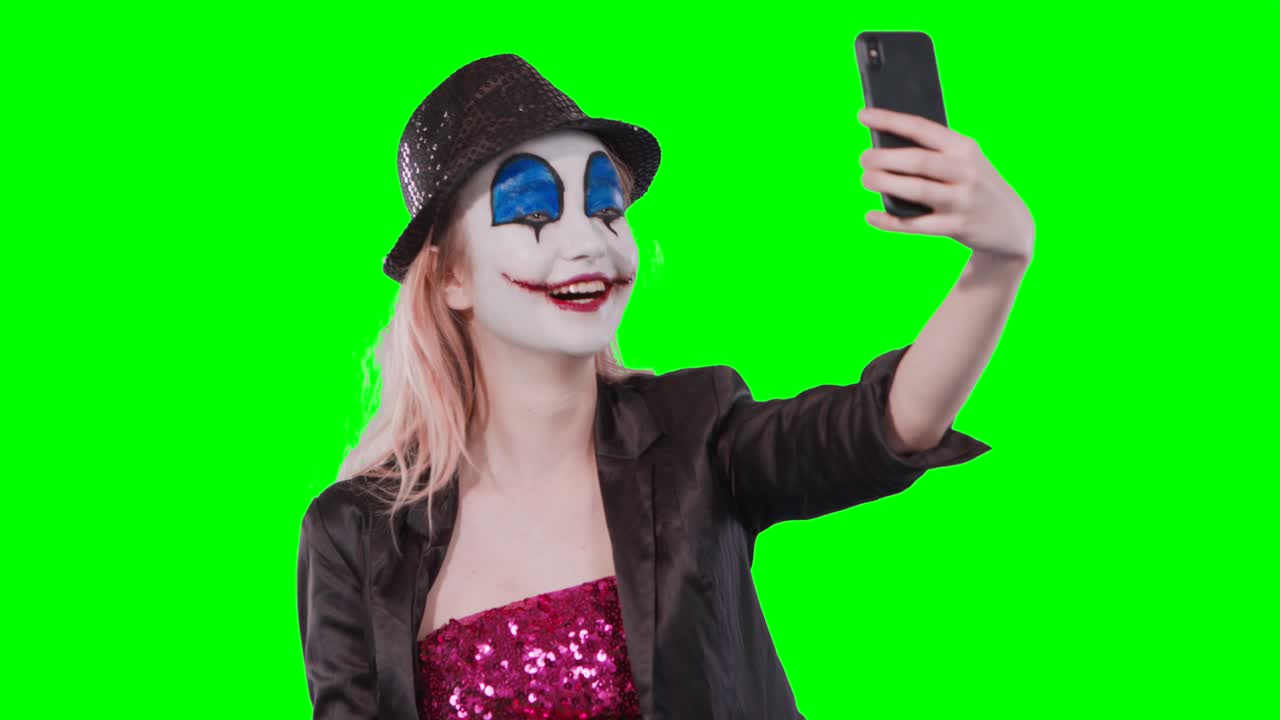 el payaso de halloween se maquilla tomando una selfie con su teléfono móvil.