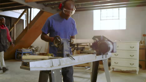 african american man operating lathe in shop aligning blank, adjusting rest, starting motor shaping