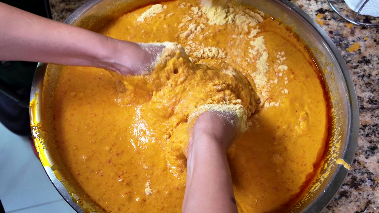 Mixing cornmeal into hallaca dough for a traditional meal prep