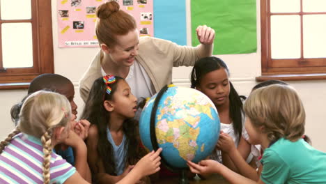 cute pupils and teacher in classroom with globe