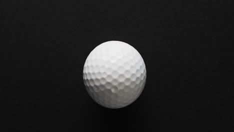 close up of golf ball on black background, copy space, slow motion