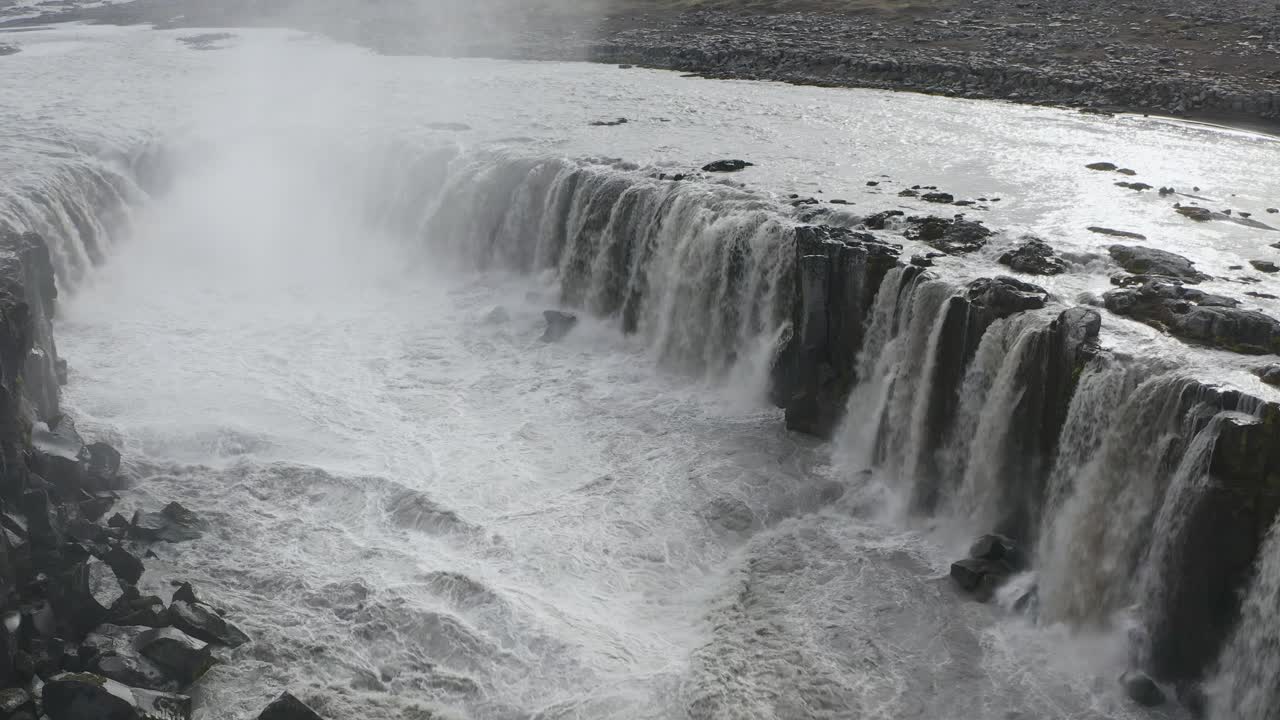 toma aérea de arriba hacia abajo de la cascada selfoss que desemboca en el río glacial jokulsa en islandia