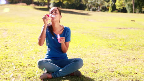una mujer bonita soplando burbujas en el parque.