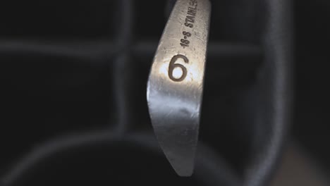 close-up shot of a 6 iron being selected from an empty golf bag