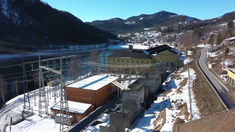 Hydroelectric-powerstation-Nore-I-electric-cables-infrastructure-and-distribution-network---Aerial-flying-towards-powerstation-and-transformer-station-in-Rodberg-with-blue-sky-and-mountain-background