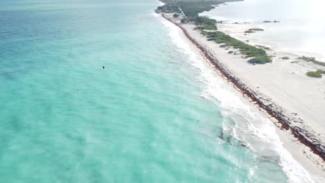 Isla-Blanca-Desde-El-Cielo,-La-Perspectiva-Aérea-Revela-Un-Cuadro-Encantador-Donde-Las-Suaves-Olas-Acarician-La-Prístina-Playa-De-Arena-Blanca.