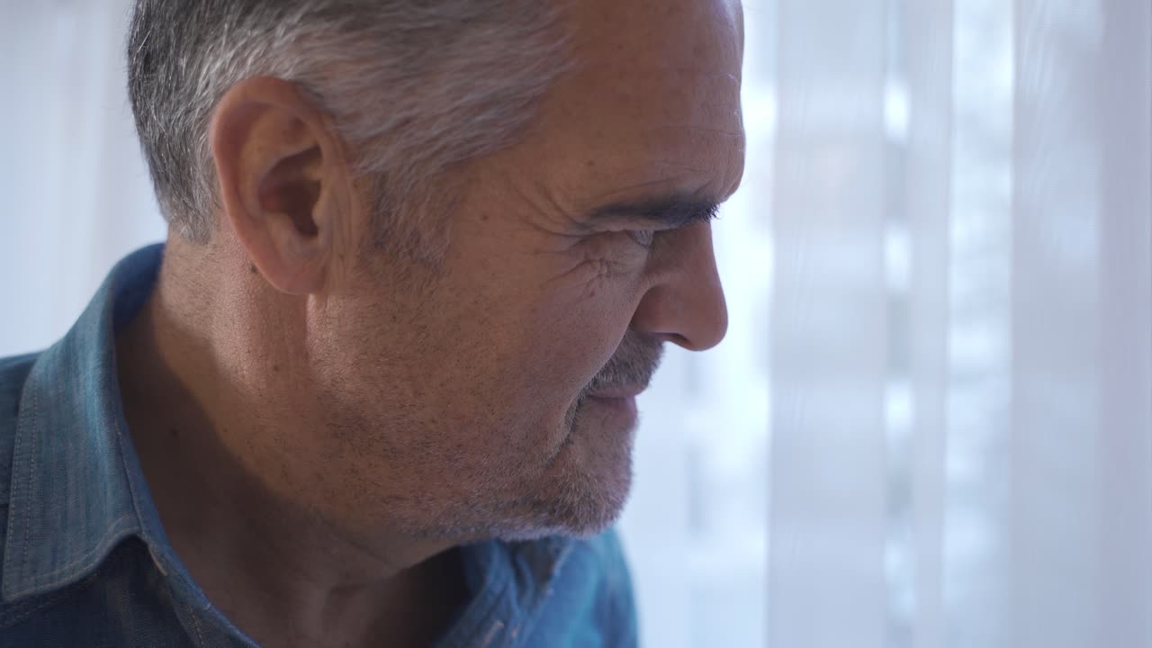 Anziano solo che guarda fuori dalla finestra