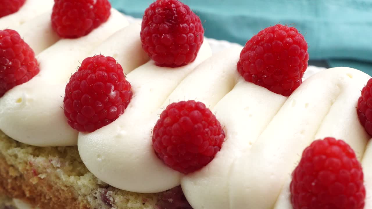 Making a dessert called Red Raspberry Tea Cake made with fresh berries and vanilla buttercream frosting. Great for Tea Parties. Close up of a piece of raspberry tea cake. Panning across the top of it