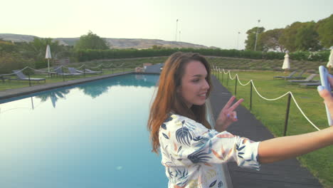 una mujer joven se toma una selfie junto a la piscina.