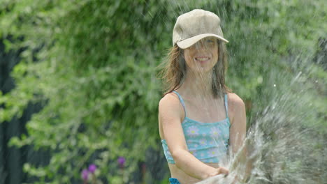 girl playing with water hose in garden