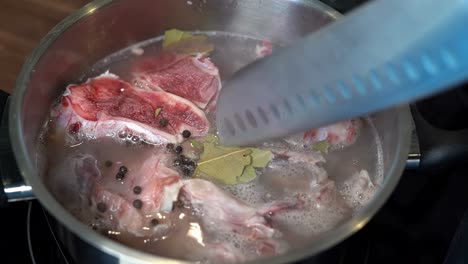 dried bay leaves pushed down into bone broth pan with knife, close-up slow motion