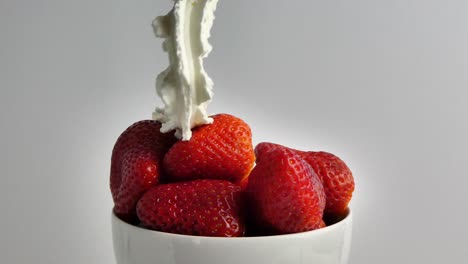una taza con fresas y una deliciosa crema cayendo sobre ellas