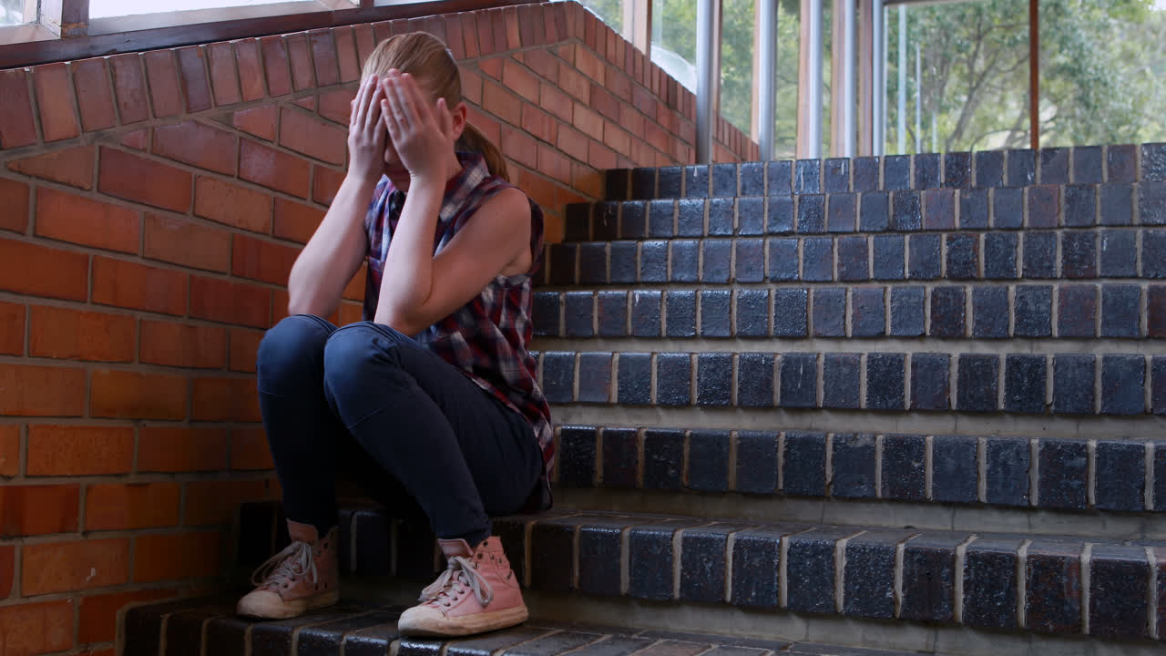 Scolara triste che si siede da solo sulla scala