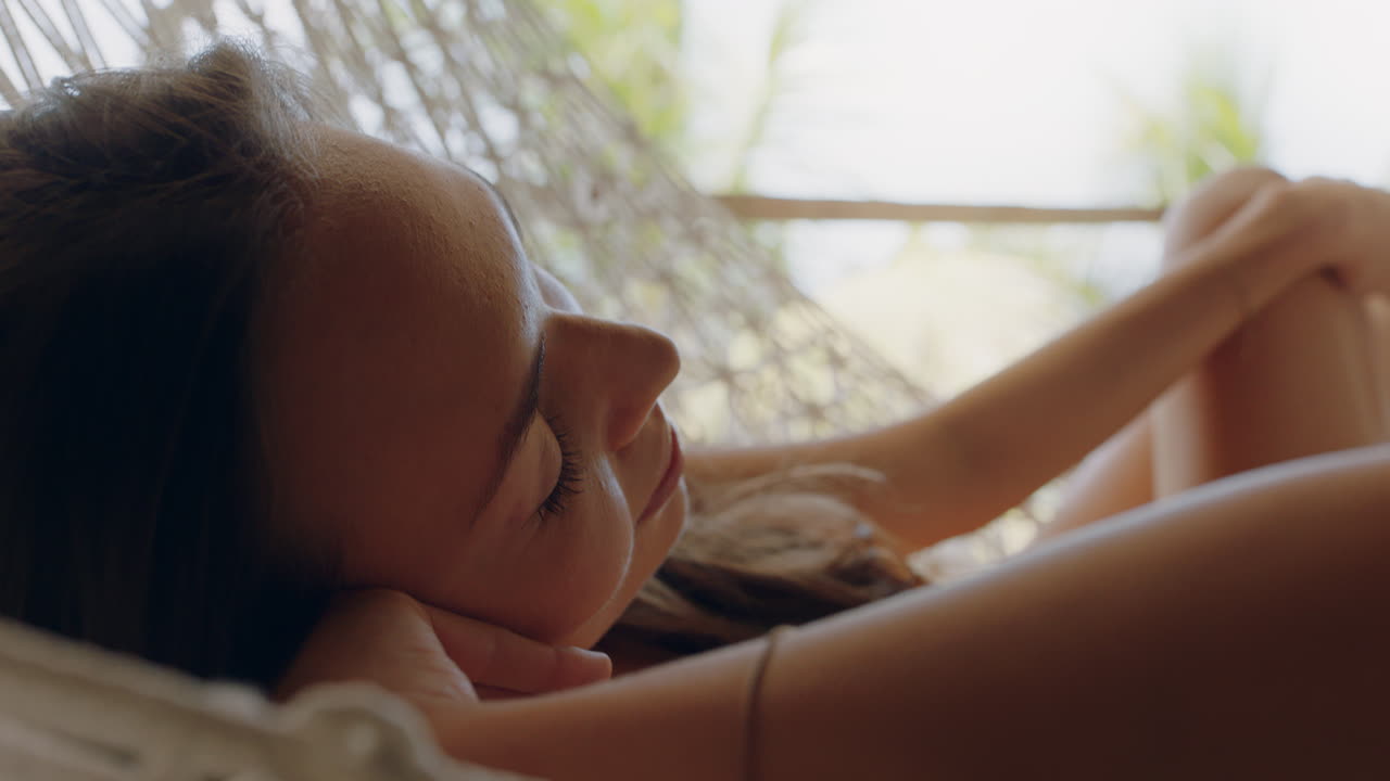 휴가 휴양지에서 휴가를 보내는 편안한 라이프 스타일을 즐기는 해마크에 있는 행복한 여성이 열대 천국 오두막에서 게으른 여름날에 평화롭게 흔들리고 있습니다.