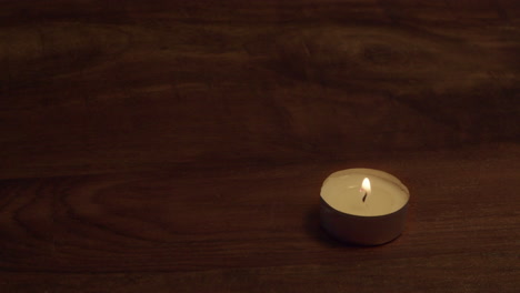 copy space wooden table top with one tea light candle in lower corner