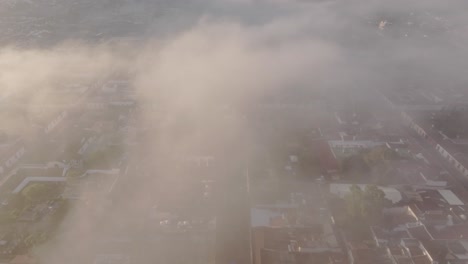 flying through low clouds towards santa catalina arch at antigua guatemala, aerial