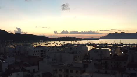 AERIAL:-Small-City-with-Port-on-Tropical-Island,-early-morning-with-Boats-and-Ocean-at-Small-Town-at-Sunrise-with-Mountains-in-Background-Vacation,-Travel,-Sunset