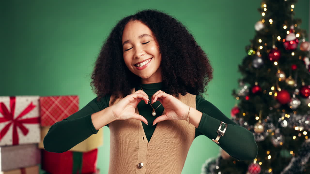 Woman Making Heart Shape in Front of Christmas Tree