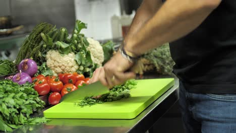 Unrecognizable-chef-cutting-fresh-leafs-of-parsley-in-restaurant-kitchen,-close-up