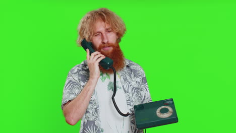 tired bored man talking on wired vintage telephone exhausted of talk making silly faces fooling