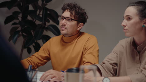 male and female colleagues sitting behind the tablet in the office, having discussion with team during late corporate meeting