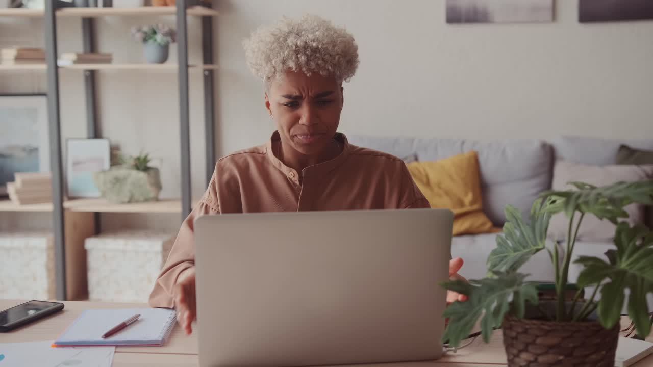 Shocked african female sit at table cover mouth with hands