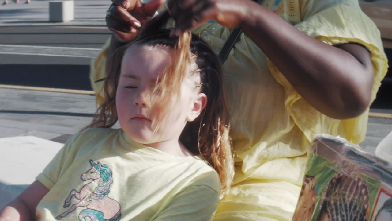 Uma menina tem o cabelo trançado na calçada da rua