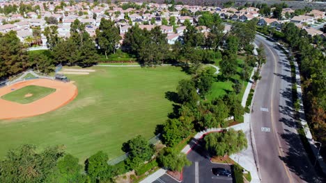 Paneo-De-Drones-Aéreos-Sobre-Y-Junto-A-Un-Campo-De-Béisbol-En-Un-Parque-Comunitario-En-Los-Suburbios