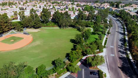 aerial drone pan over and by a baseball field at a community park in the suburbs