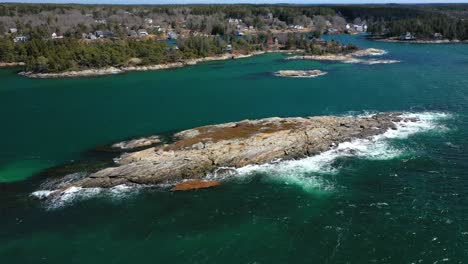 volando más allá de una pequeña isla rocosa estéril de la costa de maine en un ventoso día de primavera