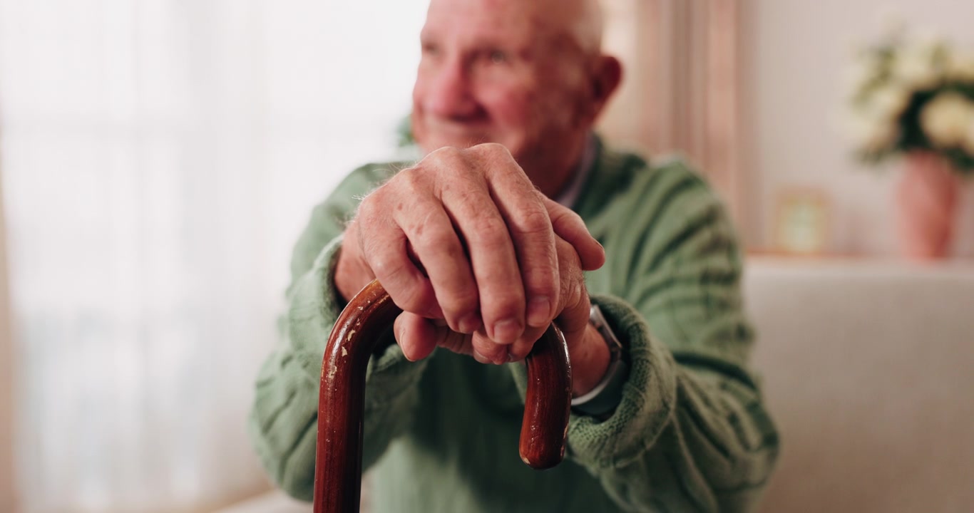Uomo anziano che appoggia le mani su un bastone da passeggio
