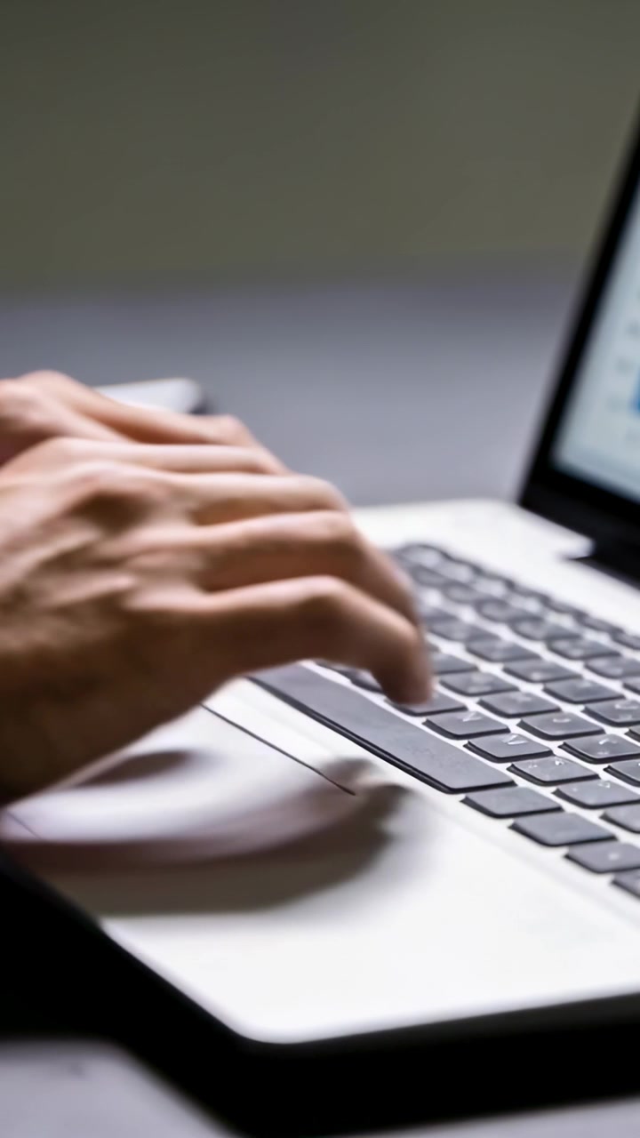 Video verticale: Mani posate con braccia scoperte che digitano sulla tastiera a una scrivania, lavorando.