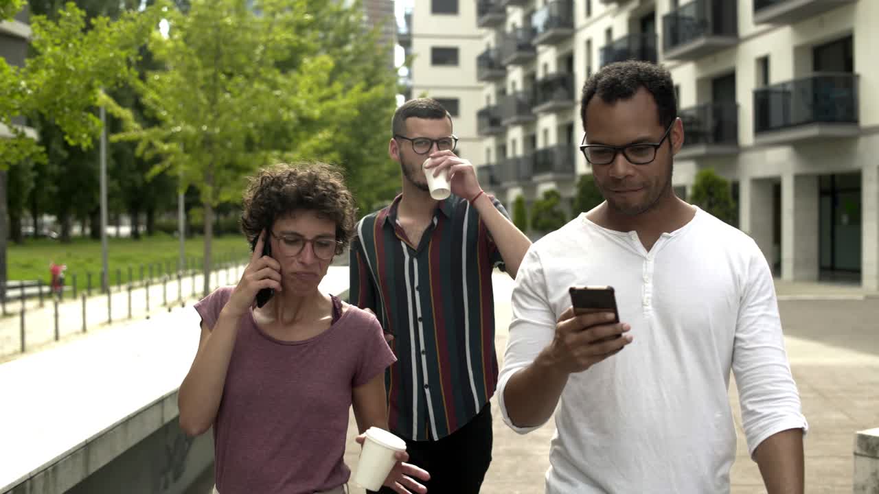 personas relajadas que usan teléfonos inteligentes mientras caminan por la calle