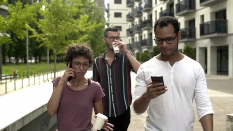 relaxed people using smartphones while walking on street