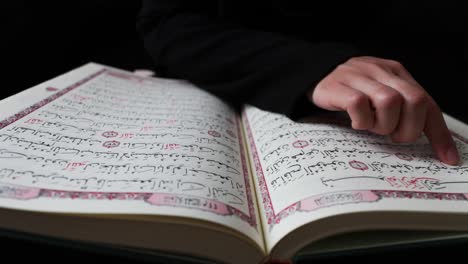 close up footage from above a quran and a person reading it, the person is tracing the verses in the quran with her finger